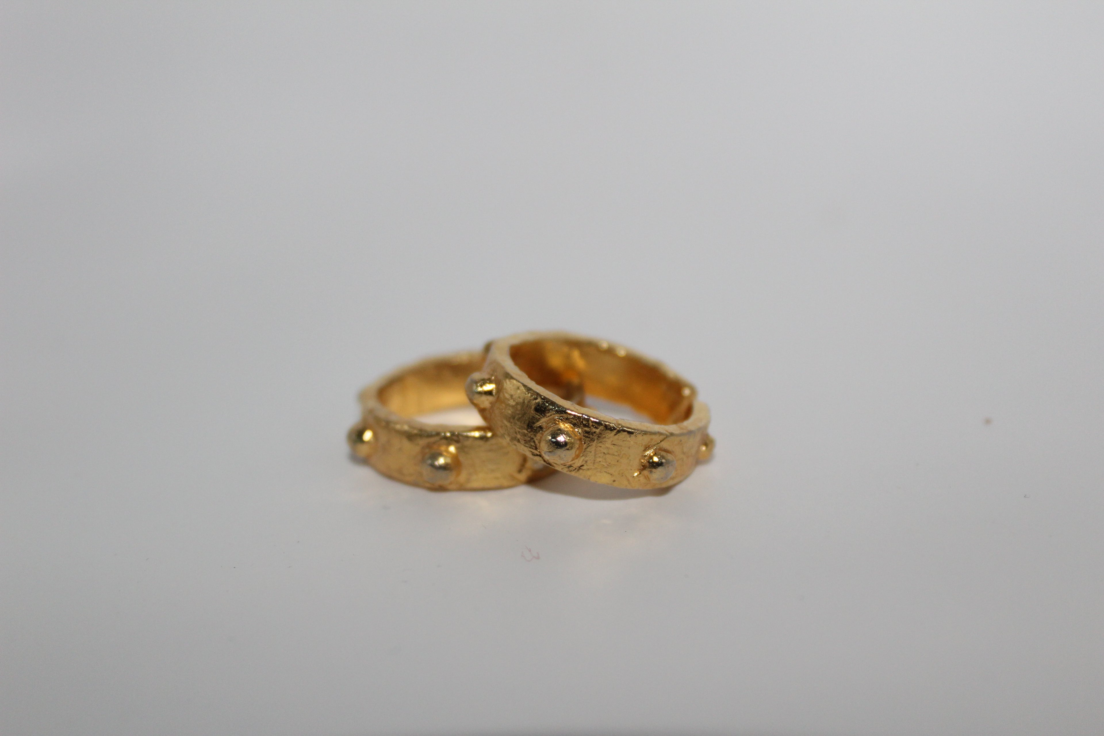 Two gold rings stacked on a light gray background